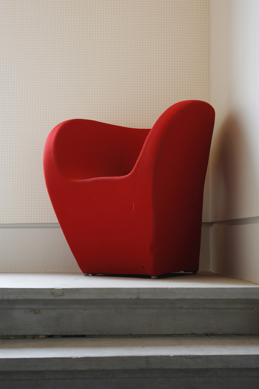 Un fauteuil rouge, installé sur le palier de l'escalier en pierre