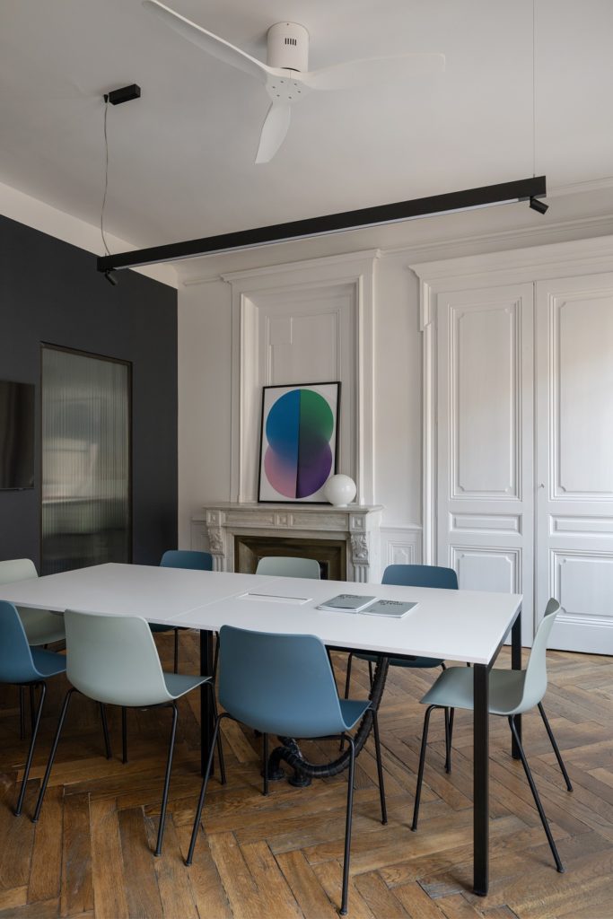 Bureau, salle de réunion avec un mur de couleur sombre, un long luminaire led noir en led au plafond.