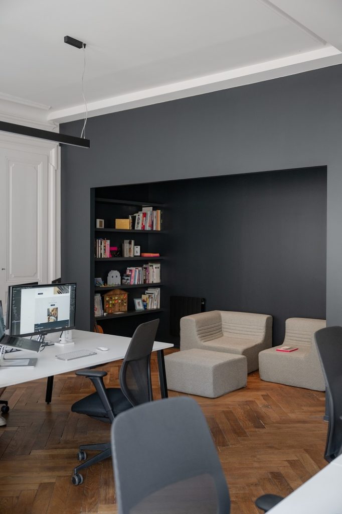 Coin détente à droite de l'open space avec une bibliothèque et un canapé.