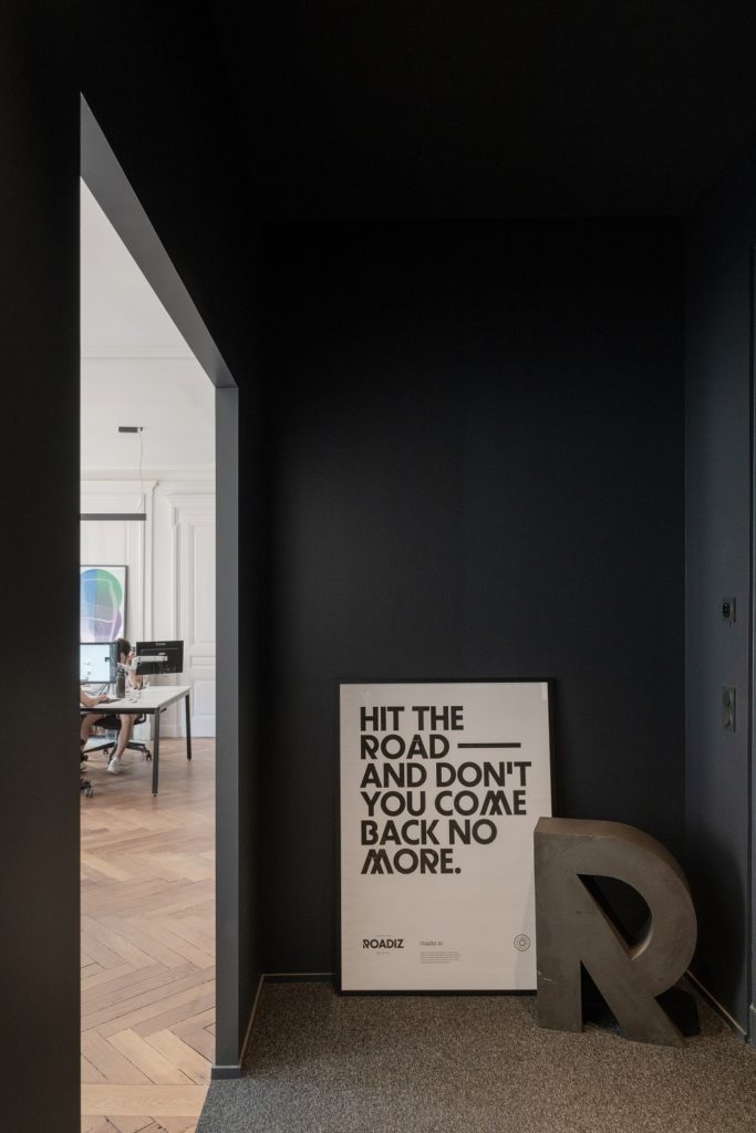 Couloir couleur foncée qui débouche sur un open space.