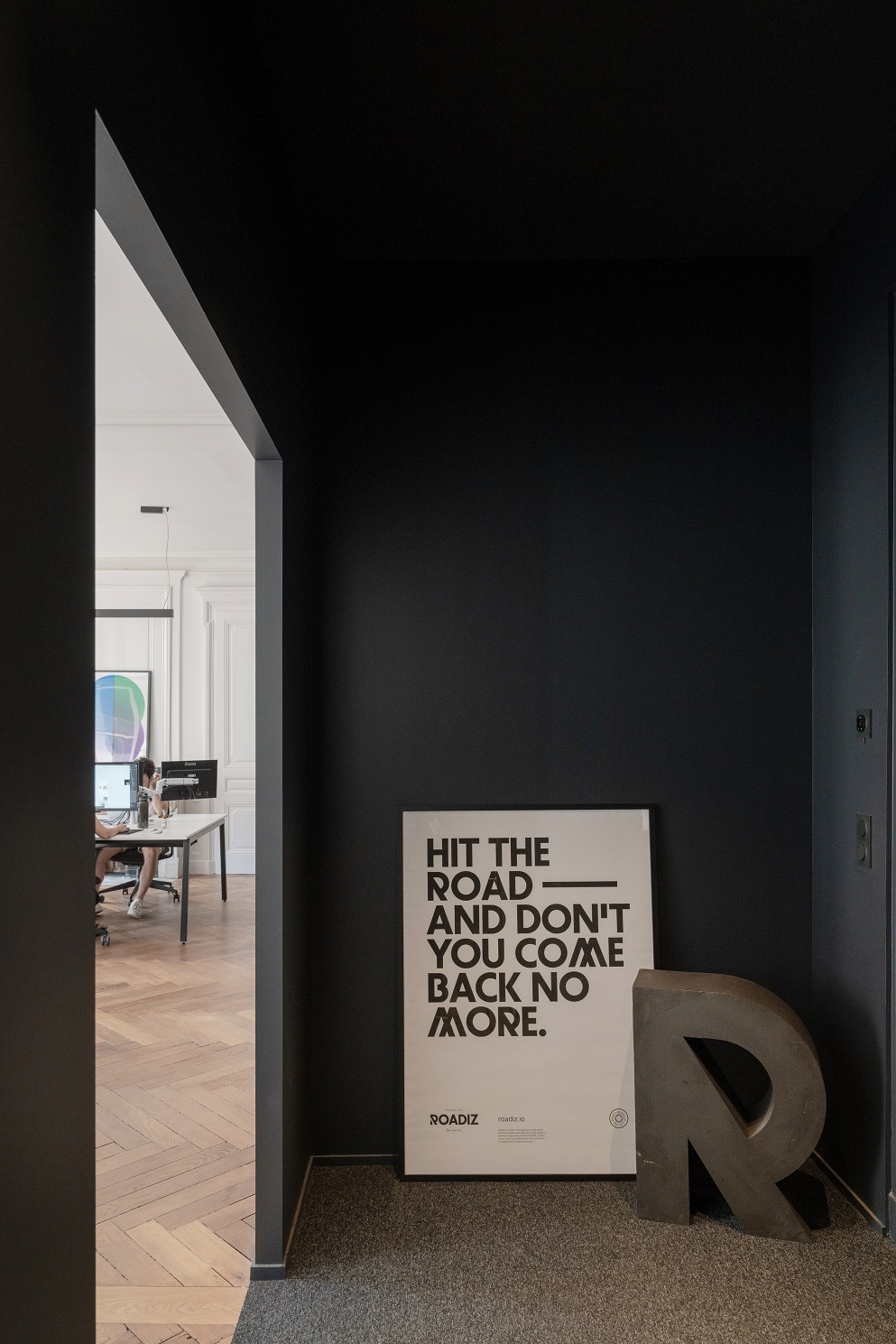 Couloir couleur foncée qui débouche sur un open space.