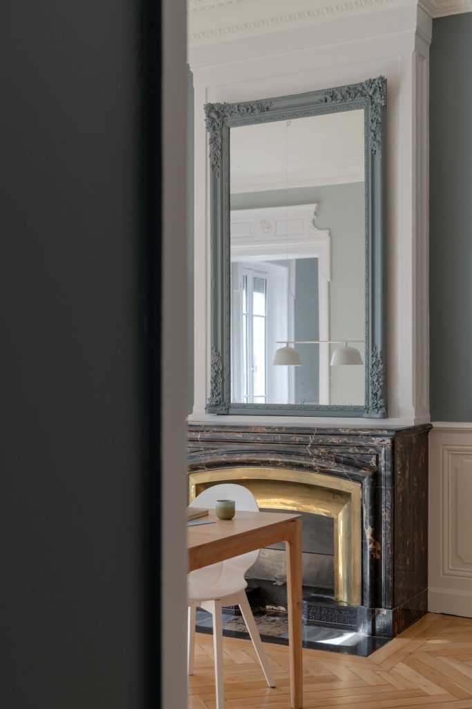 Cheminée réhaussée d'un miroir peint dans les mêmes teinte que l'appartement.
