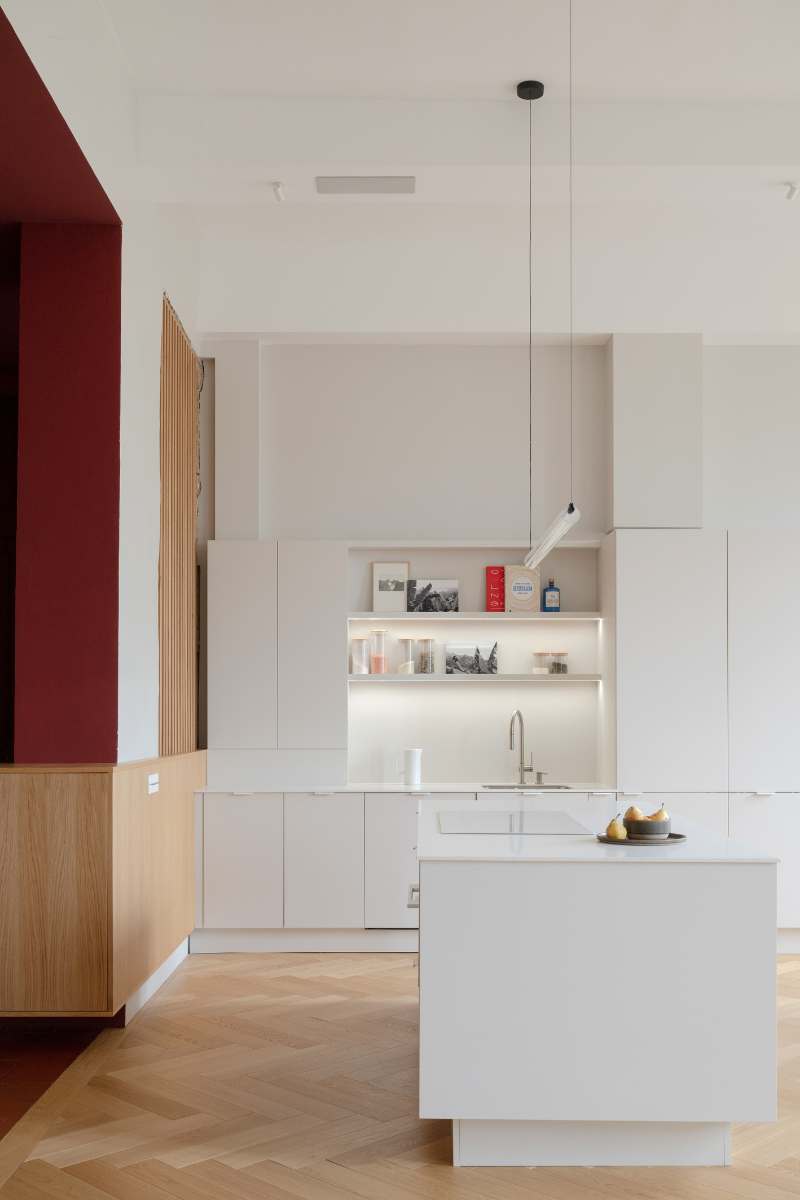 Vue de profile de la cuisine avec un luminaire tubulaire au dessus de l'ilot central.